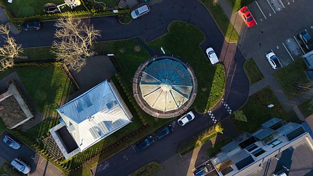 High angle aerial view of a historic lighthouse tower nestled within a modern Tallinn neighborhood. A beautiful blend of heritage architecture and urban living at golden hour.