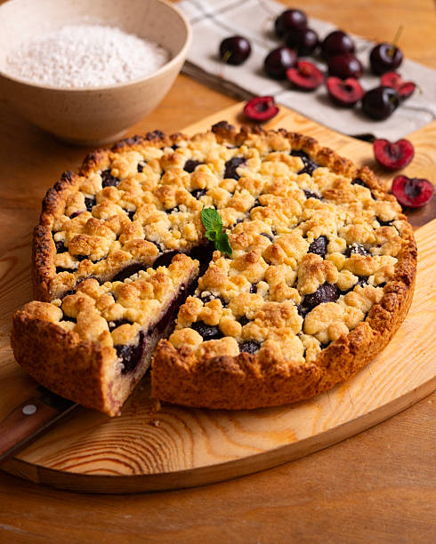 Delicious homemade cherry crumble pie with fresh mint garnish on a wooden board