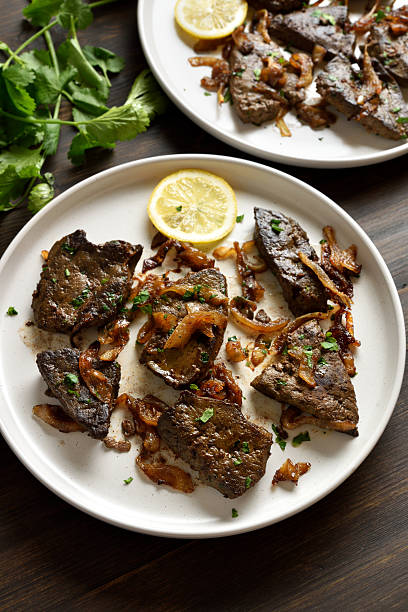 Roasted  liver with onion on plate on brown wooden table