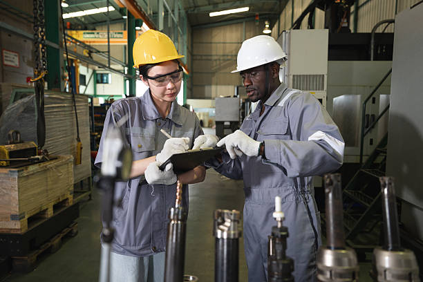 Two engineer man and woman working with tablet computer and control machine at auto parts factory