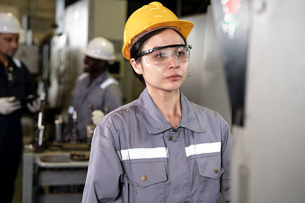 Woman engineer working and control machine with team engineer background at auto parts factory