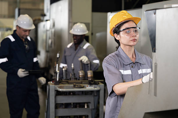 Woman engineer working and control machine with team engineer background at auto parts factory