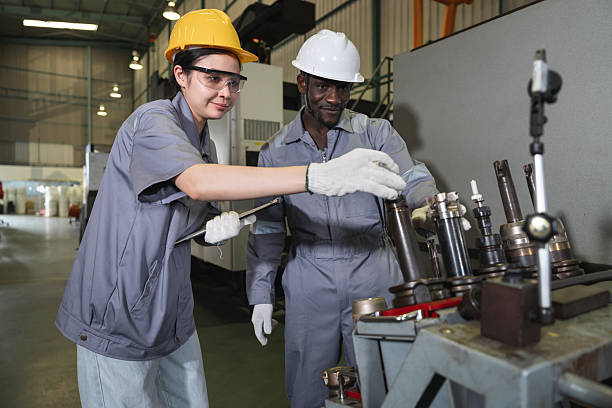 Two engineer man and woman working with tablet computer and control machine at auto parts factory