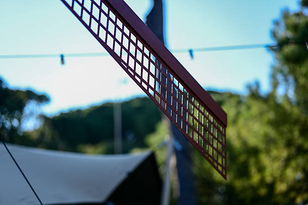 Windmill sail featuring a patterned grid against a vibrant blue sky and green trees