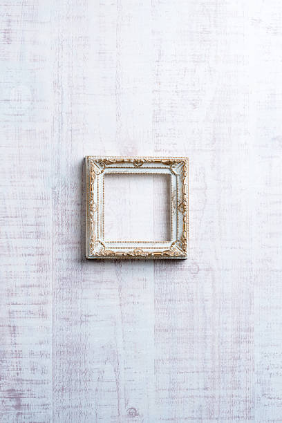 Ornate vintage white and gold square frame on white wooden background with copy space