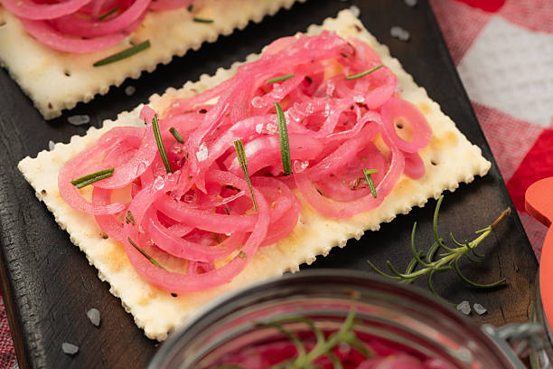Cracker with pickled red onions and rosemary on rustic wooden board