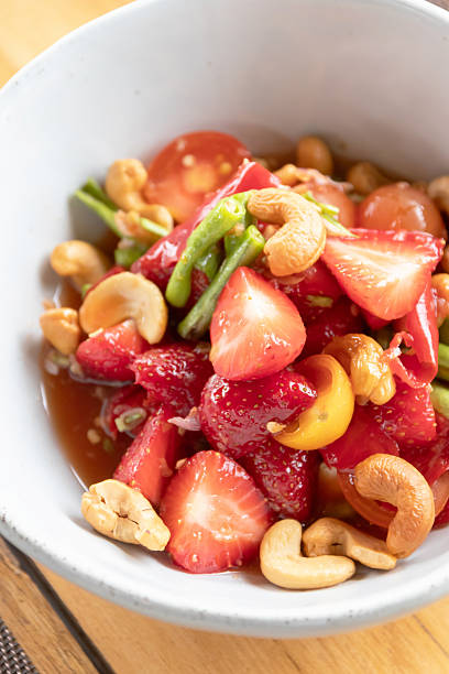 Strawberry salad with cashew and green bean in tangy dressing, fresh vibrant fruit and nut salad with cherry tomato bite