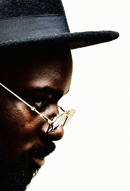 A contemplative portrait of a black man in sharp side light, defined by texture, restraint, and understated elegance—where identity emerges through silhouette and detail.