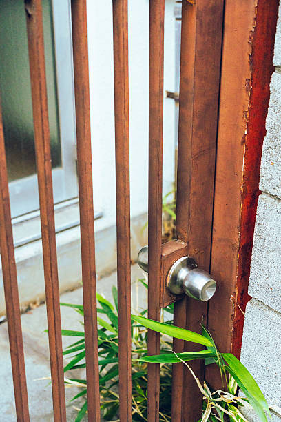A close-up of a wooden gate with a metal door handle, highlighting rustic textures and subtle signs of aging. The image conveys themes of entrance, privacy, security, and everyday life, suitable for architectural and lifestyle concepts.