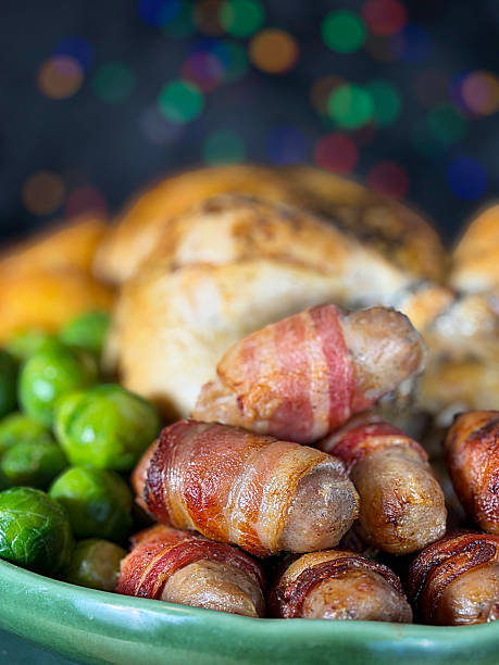 Full frame image Sunday roast / Christmas dinner, all the trimmings on green serving dish, whole roast chicken, surrounded by side dishes of Brussel sprouts, roast potatoes, pigs in blankets, illuminated multicoloured fairy light background