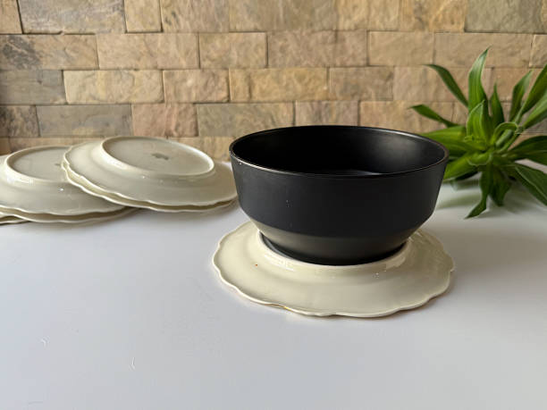Modern black bowl stacked on vintage-style scalloped side plates - Table setting