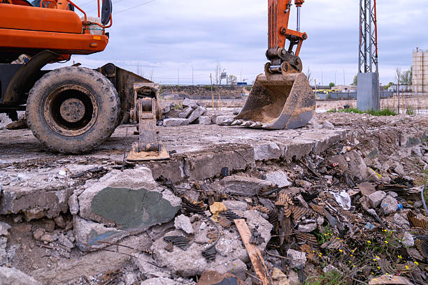 Industrial excavator breaking concrete and rubble at a construction demolition project