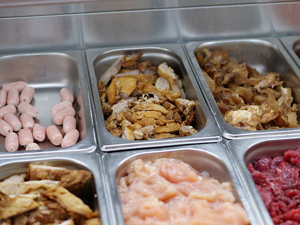 A high-angle, close-up shot captures an organized display of raw and cookedmeats in stainless steel Gastronorm containers at a buffet or hot pot restaurant.