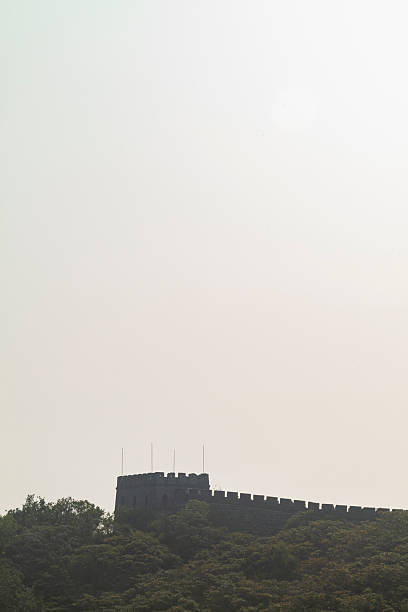 Remote watchtower along the historic Great Wall of China, a stone national landmark, against a hazy sky, representing ancient heritage and travel destination