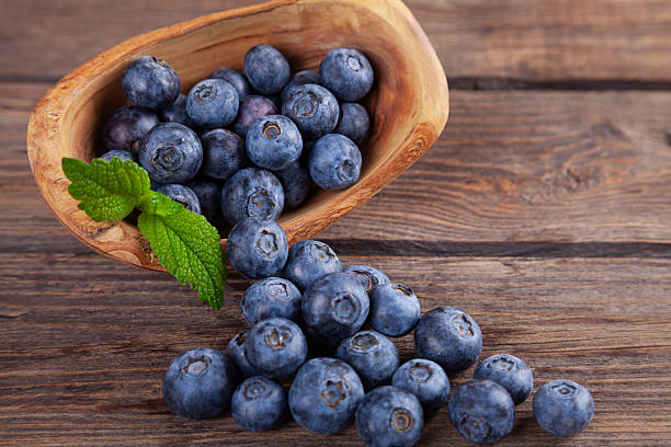 Blueberries with mint leaves scattered from basket on wooden rustic table