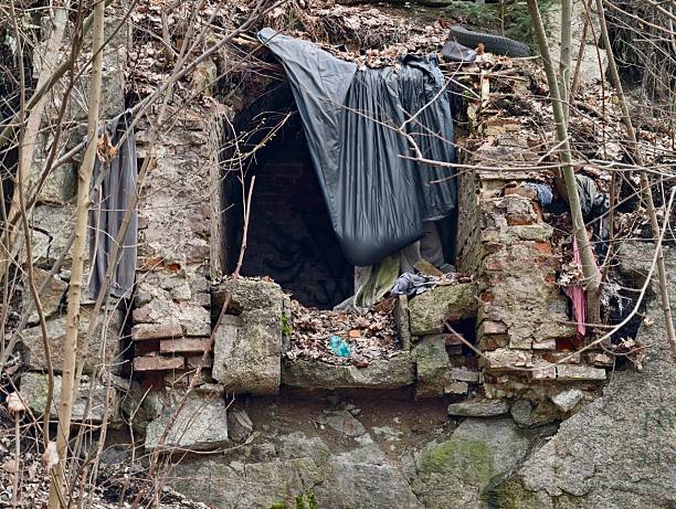 Ruin window shelter draped with tarp concealing cluttered interior of broken masonry, scattered plastic
