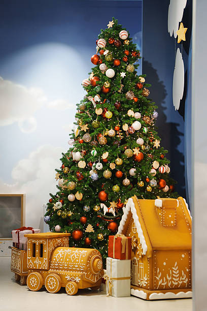 A tall Christmas tree stands with colorful ornaments and lights