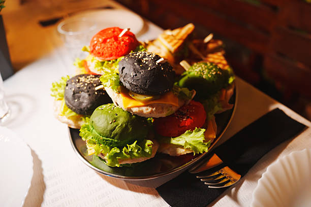 Colorful burgers with various toppings on a silver platter at a restaurant