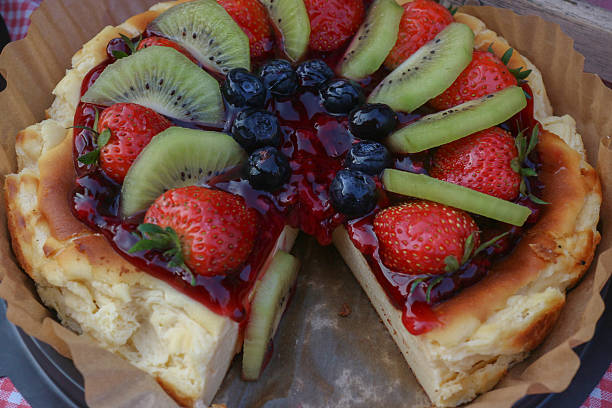 Mixed fruit tart with kiwi, strawberries, and blueberries on buttery crust. Fresh bakery dessert with vibrant colors and glossy finish.