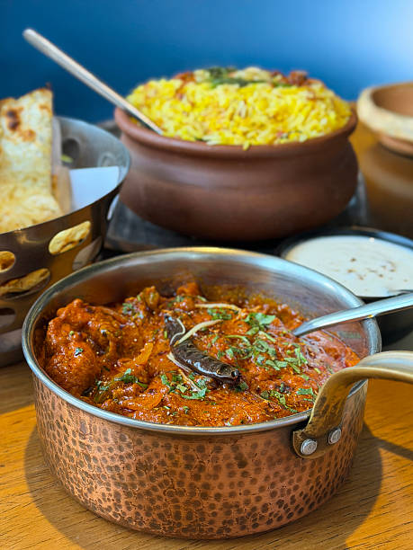 Image of fragrant biryani rice with soft parathas, naan bread, served, kadhai chicken tikka masala, creamy butter chicken curry, authentic Indian meal
