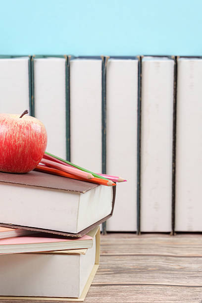 Stack of books with apple and pencils
