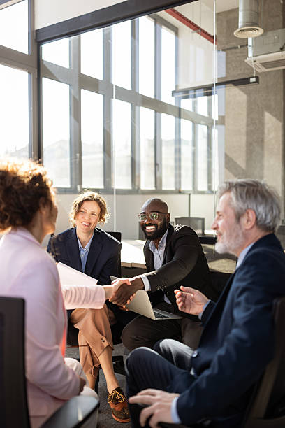 Smiling Diverse Business Team Shaking Hands During Casual Office Meeting In Modern Conference Room