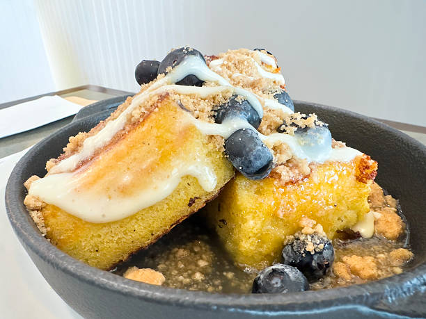 Warm cornbread served in a cast iron skillet with cream glaze, blueberries and crumble topping