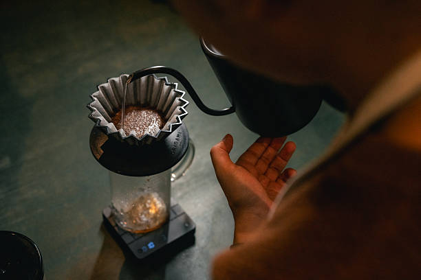 Close-up shot of skilled barista using a hand coffee grinder at a cafe