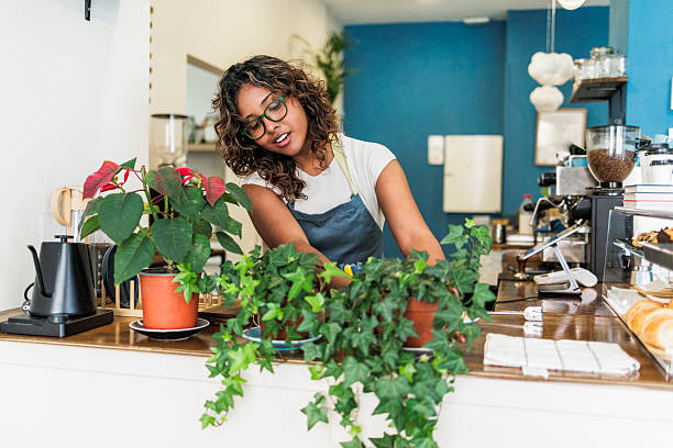 Barista tending plants creating inviting cafe atmosphere