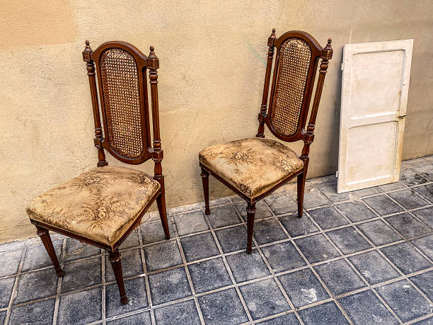 High angle close-up view of two antique chairs side by side abandoned in the street in the city of Valencia, Spain.