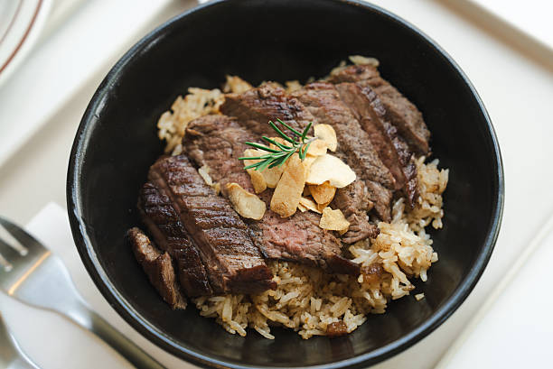 Sliced steak served on rice in a bowl