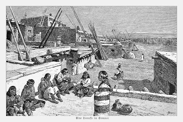 Authentic 19th-century engraving depicting a summer scene in a Zuni Pueblo village, likely in New Mexico. A group of Native American men and women are gathered on a rooftop terrace, engaged in daily activities and crafts. The background shows the characteristic adobe architecture with ladders used to access the different levels of the pueblo. The original German caption reads 'Eine Terrasse im Sommer' (A terrace in summer).