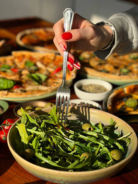 Image of fresh rocket salad leaves complement vibrant pizza buffet with mixed pizzas, assorted toppings, olives, olive oil, tomatoes