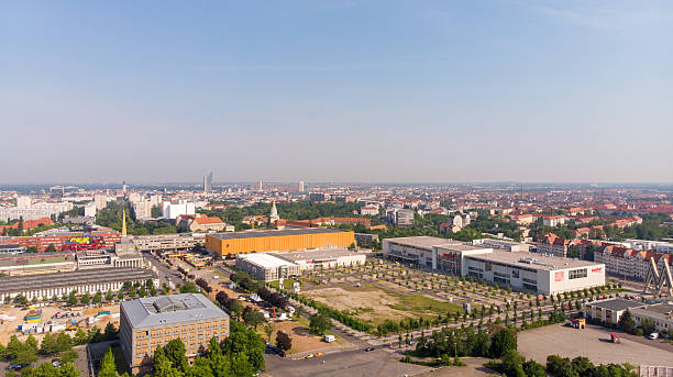 Aerial drone view of Alte Messe Leipzig in Saxony, Germany, captured on a sunny day. Historic trade fair grounds with exhibition halls, open spaces and surrounding urban landscape. Architecture, cityscape, tourism, events and European heritage concept.