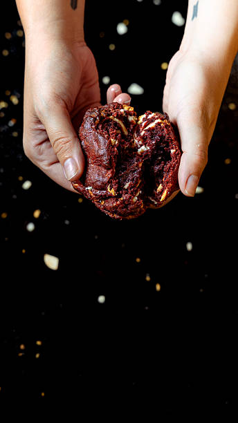 Hands breaking red velvet cookie with crumbs falling