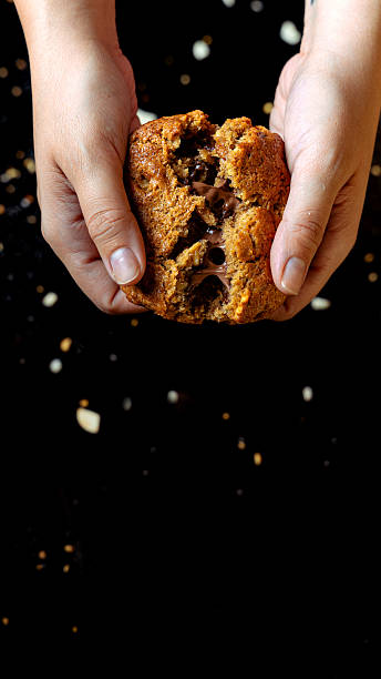 Hands breaking warm chocolate chip cookie overflowing with melted chocolate