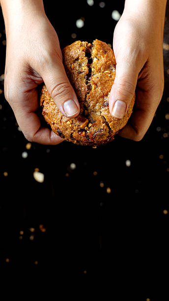 Hands breaking homemade chocolate chip cookie in half