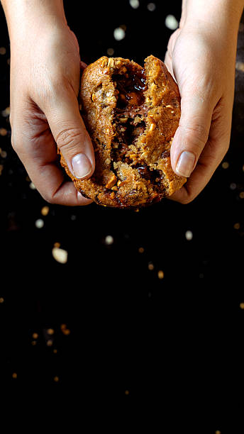Hands breaking fresh chocolate chip cookies with gooey filling