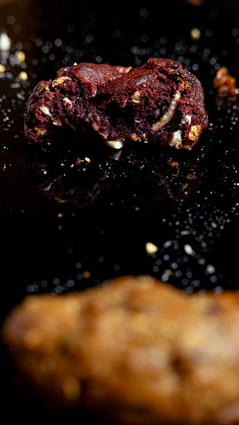 Red velvet cookie with white chocolate chips on dark reflective surface