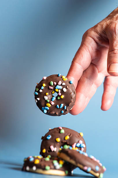 Hand Reaching for Colorful Chocolate Donuts