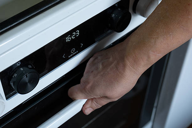 Adjusting oven temperature – close-up of hand on kitchen appliance