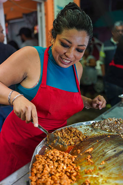 Latin woman cooking street food tacos on griddle