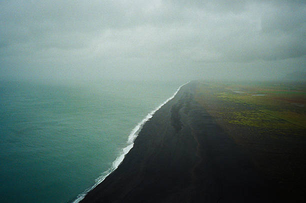 Dramatic view of black sand beach and stormy ocean from above in Dyrholaey, South Iceland. Shot by point and shoot 35mm camera