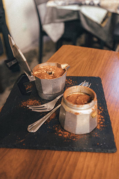Tiramisu dessert served in moka pots on rustic table in cozy cafe interior