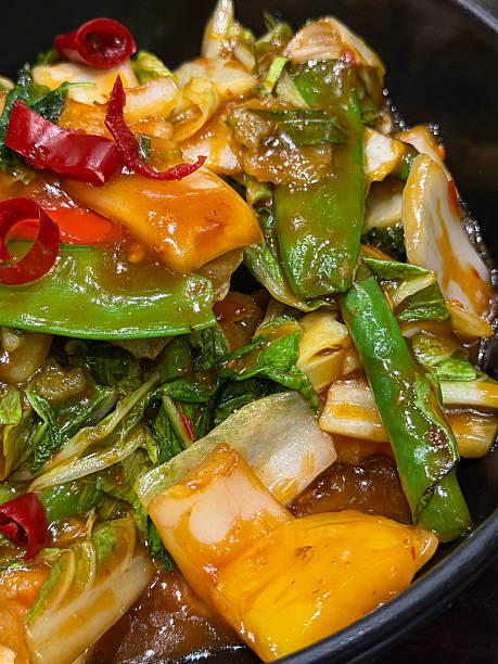 Image of colorful thai mixed vegetable stir-fry with peppers, broccoli, sugar snap peas, french beans, onions, and red chilies, vibrant Asian dish