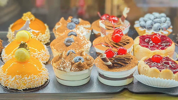 Assorted pastries, dessert cakes displayed in bakery case with cherries, blueberries, cream, glaze, fruit toppings. Concept of pastry selection, pastry shop, cafe dessert, catering. Swett background Assorted pastries, dessert cakes displayed in bakery case with cherries, blueberries, cream, glaze, fruit toppings. Concept of pastry selection, pastry shop, cafe dessert, catering. Swett background