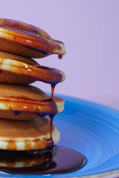 Pancakes stack with syrup dripping on a blue plate Pancakes stack with syrup dripping on a blue plate