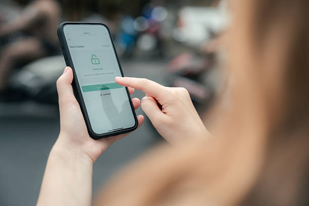 gros plan d’une touriste qui entre un code d’accès numérique sécurisé dans une application intelligente sur son téléphone intelligent pour accéder à distance à sa chambre d’hôtel - facilité daccès photos et images de collection
