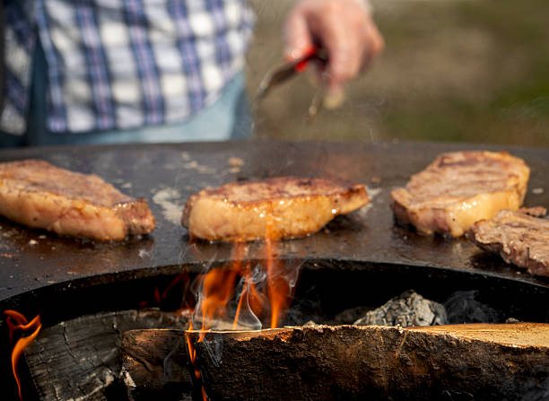 Flames dance beneath sizzling steaks on a rustic grill Flames dance beneath sizzling steaks on a rustic grill