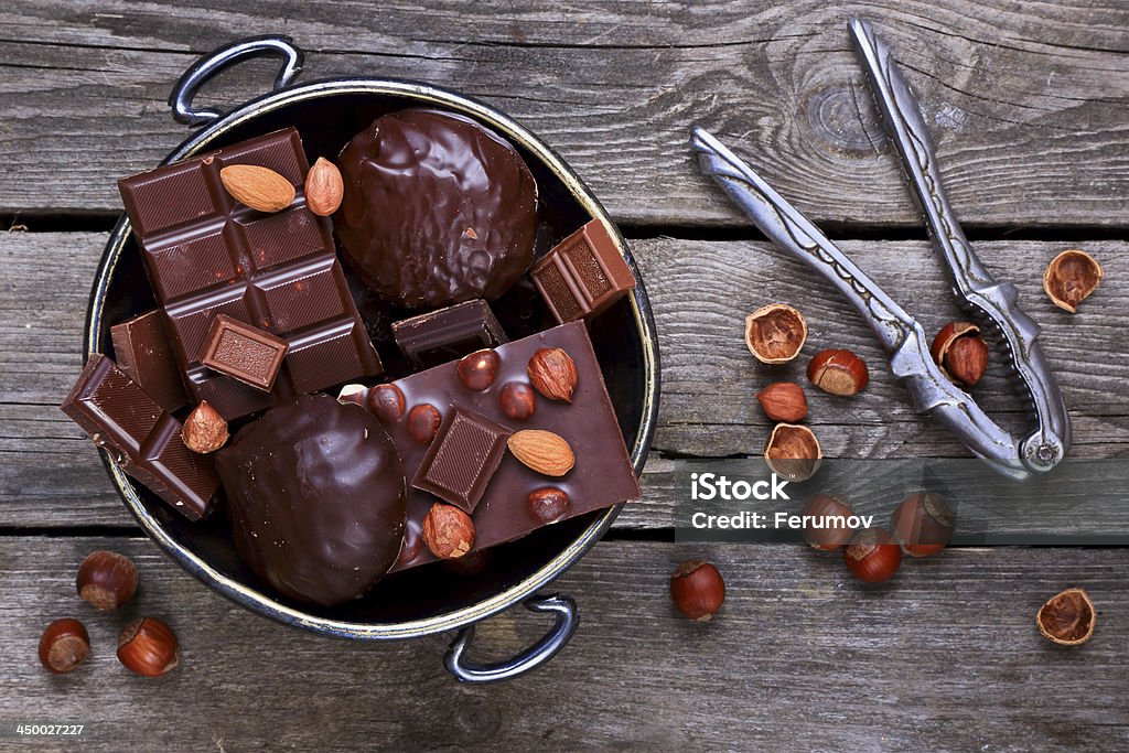 Vase with chocolate and nuts Vase with chocolate, nuts and nutcracker on a gray wooden background Candy Stock Photo